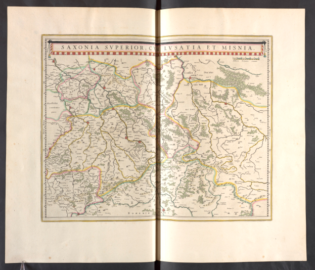 Ein aufgeschlagenes Buch mit einer detaillierten Karte von Sachsen, die ihre Provinzen und Städte hervorhebt, vor einem schwarzen Hintergrund.