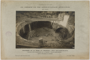 Schwarzes und weißes Foto eines im Bau befindlichen Tunnels mit einem Stempel links und Text unten.