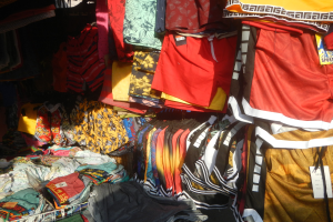 Ein Marktstand mit bunten Kleidern wie T-Shirts und Shorts mit Preisschildern.