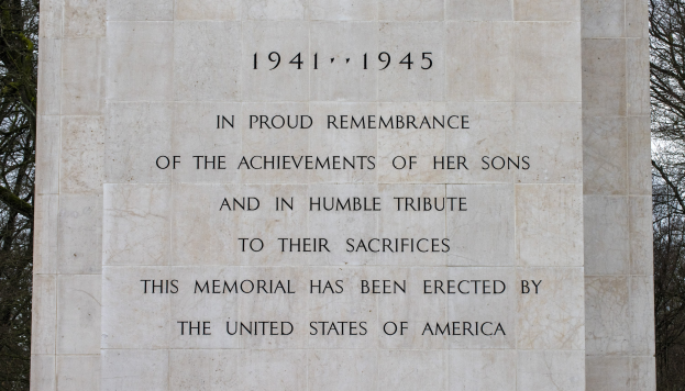 Ein Denkmal mit einer Tafel, auf der steht: "In stolzem Gedenken an die Leistungen ihrer Söhne und in bescheidener Ehrung ihres Opfers" vor einem Hintergrund aus Bäumen und einem klaren blauen Himmel.