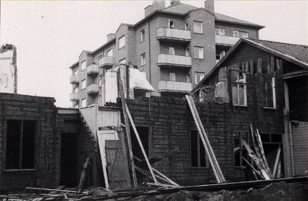 Ein Schwarz-Wei├č-Foto der abgerissenen West End Apartments mit Schutt auf dem Boden und dem Himmel im Hintergrund.