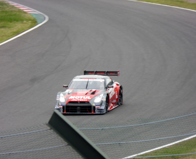 Ein Nissan GT-R Nismo GT3 Rennauto auf der Nürburgring 24 Stunden Rennstrecke mit grünem Gras auf beiden Seiten.