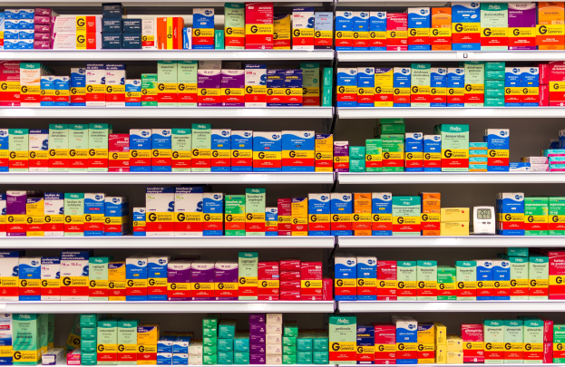 Ein Apothekenregal mit verschiedenen Medikamenten, Schachteln und Gegenständen, die ordentlich auf Gestellen angeordnet sind.