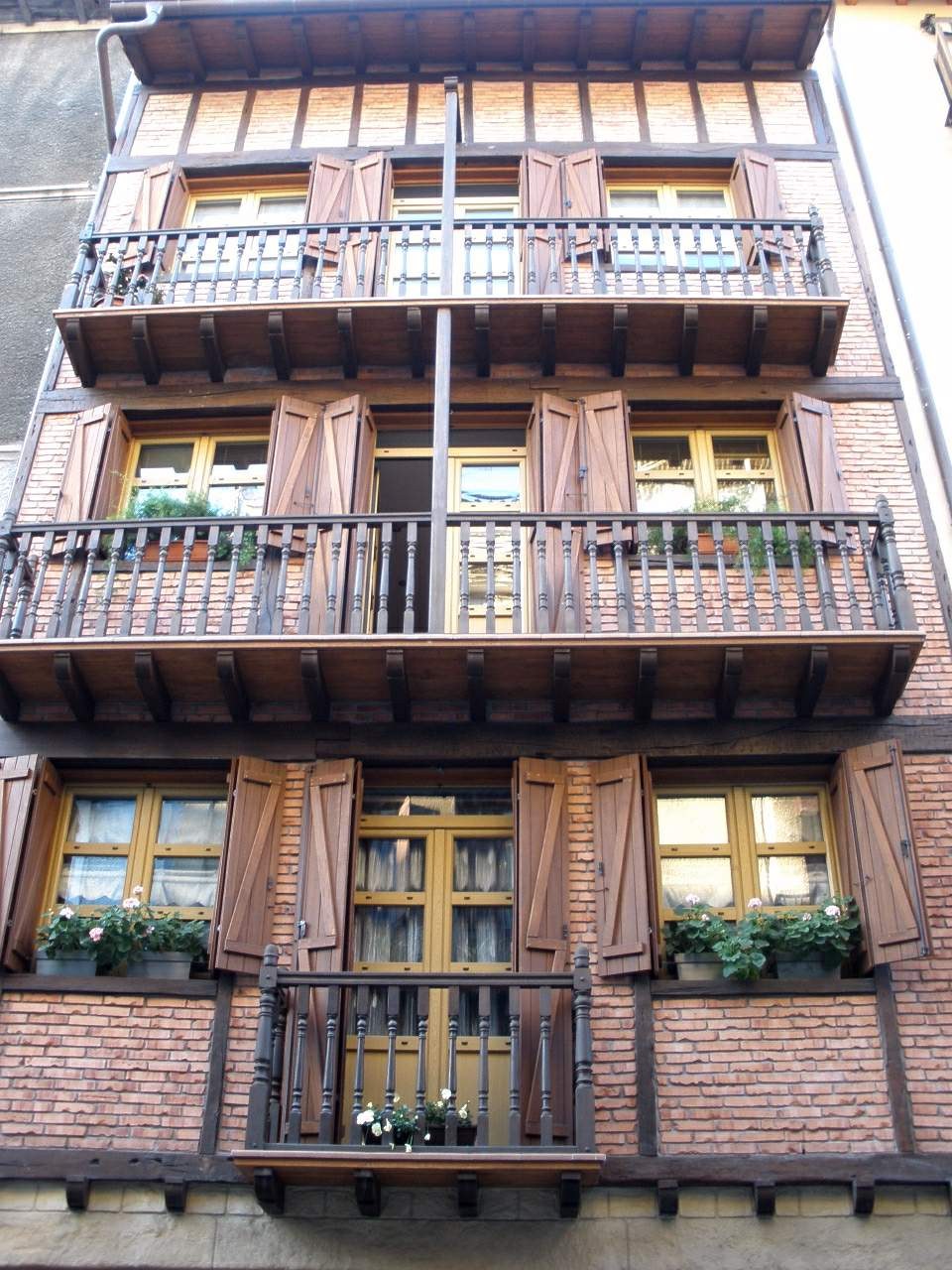 Ein mehrstöckiges Gebäude mit zahlreichen Fenstern, Balkonen, Geländern, Türen und Blumenkübeln mit Pflanzen in Straßburg, Frankreich.