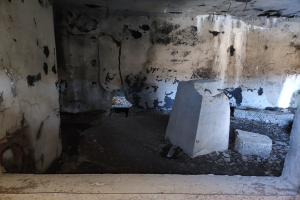 Ein Raum mit umfangreichen schwarzen Schimmel an den Wänden und auf dem Boden, der verstreute Betonblöcke enthält, scheint das Innere eines Gebäudes zu sein, das durch einen israelischen Luftangriff beschädigt wurde.