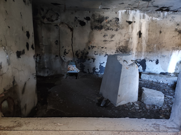 Ein Raum mit umfangreichen schwarzen Schimmel an den Wänden und auf dem Boden, der verstreute Betonblöcke enthält, scheint das Innere eines Gebäudes zu sein, das durch einen israelischen Luftangriff beschädigt wurde.