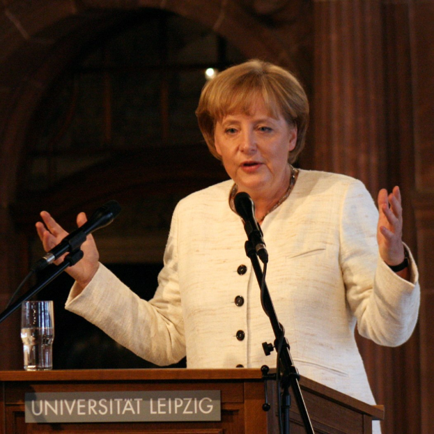 Bundeskanzlerin Angela Merkel bei einer Rede an einem Rednerpult mit einem Mikrofon und einem Glas Wasser an der Universität Leipzig.