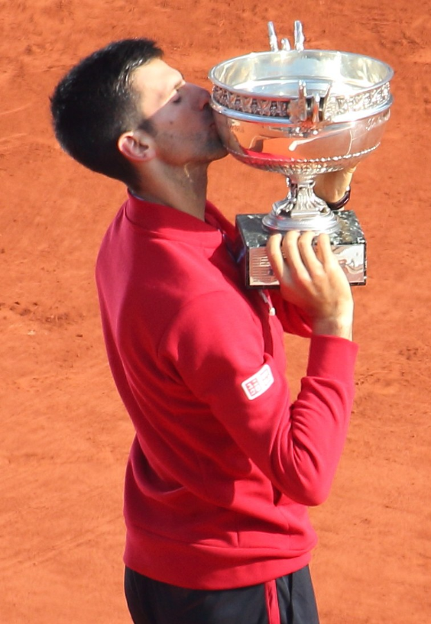 Novak Djokovic hält den French-Open-Pokal nach seinem Sieg gegen Rafael Nadal im Finale der Herren-Einzel, küsst den Pokal mit einem triumphierenden Ausdruck.