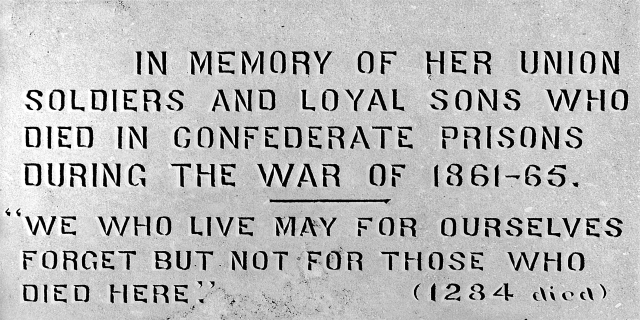 Ein Schwarz-Weiß-Foto einer Steinplatte an einem Gebäude, auf der ein Text eingraviert ist, der Union-Soldaten und treue Söhne ehrt, die während des Kriegs von 1861-65 in konföderierten Gefängnissen starben.