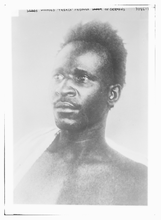 Ein Schwarz-Weiß-Foto eines Mannes mit ernstem Gesichtsausdruck, mit dem Text "Seneg Verletzter französischer Gefangener unter Deutschen" oben.
