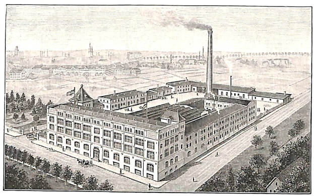 Ein altes Fabrikgebäude umgeben von Bäumen mit Text am unteren Bildrand.