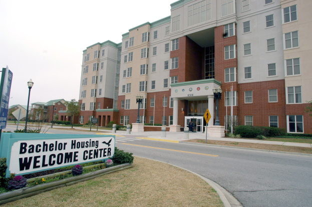 Ein Willkommenszentrum für Bachelor-Wohnen mit Gebäuden, Straßeninfrastruktur, Fahrzeugen, Grünflächen und einem klaren Himmel.