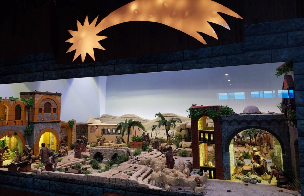 Eine Krippe in einem Museum mit Menschen, Tieren, Häusern, Bäumen und anderen Gegenständen, beleuchtet von oben.