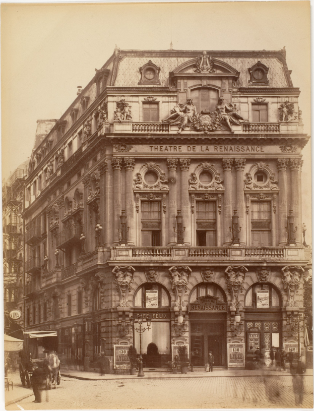 Altes Foto des Théâtre de la Renaissance in Paris, das ein Gebäude mit Fenstern, Säulen, Bögen und skulpturalen Verzierungen an der Fassade zeigt, mit ein paar Menschen und Fahrzeugen auf der Straße davor und dem Himmel im Hintergrund.