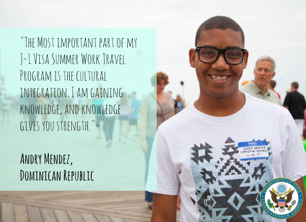 Eine Person in einem weißen T-Shirt lächelt, während sie mit einer Gruppe auf einer hölzernen Oberfläche geht, mit einem Zitat über kulturelle Integration von Andry Mendez auf der linken Seite, Gebäuden und einem klaren blauen Himmel im Hintergrund.