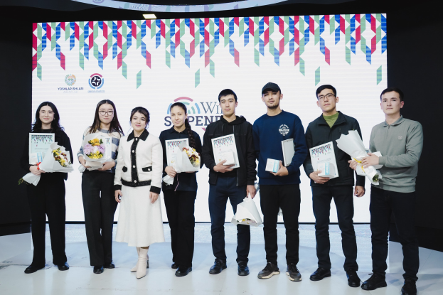 Gruppe von Menschen auf einer Bühne mit Bücher und Blumensträußen in den Händen, im Hintergrund ein Bildschirm mit der Aufschrift "Yogyakarta International School of Science and Technology"