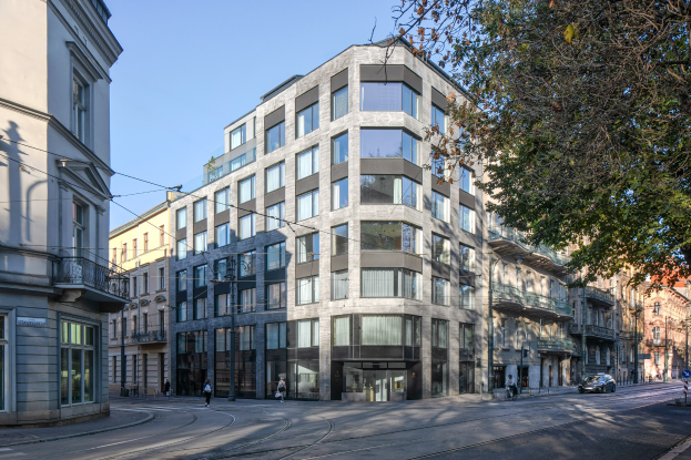 Großes Bürogebäude mit zahlreichen Fenstern, umgeben von Straßeninfrastruktur, Fahrzeugen, Fußgängern, Bäumen und einem bewölkten Himmel, das als neuer Firmensitz dient.