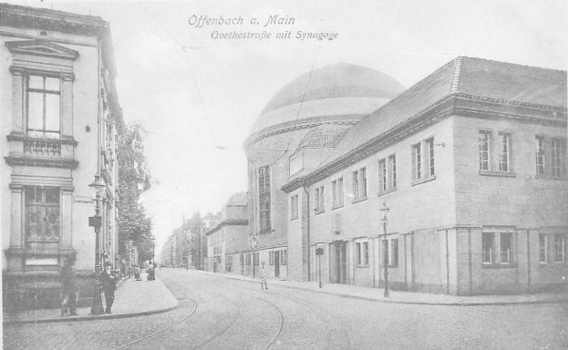 Schwarz-weiß-Foto einer Stadtstraße in Offenbach am Main, das Goethestraße mit Gebäuden, Straßenlaternen, Straßenlaternen, Bäumen und Passanten zeigt, mit dem Text "Offenbach a Main, Goethestraße mit Synagoge" oben.